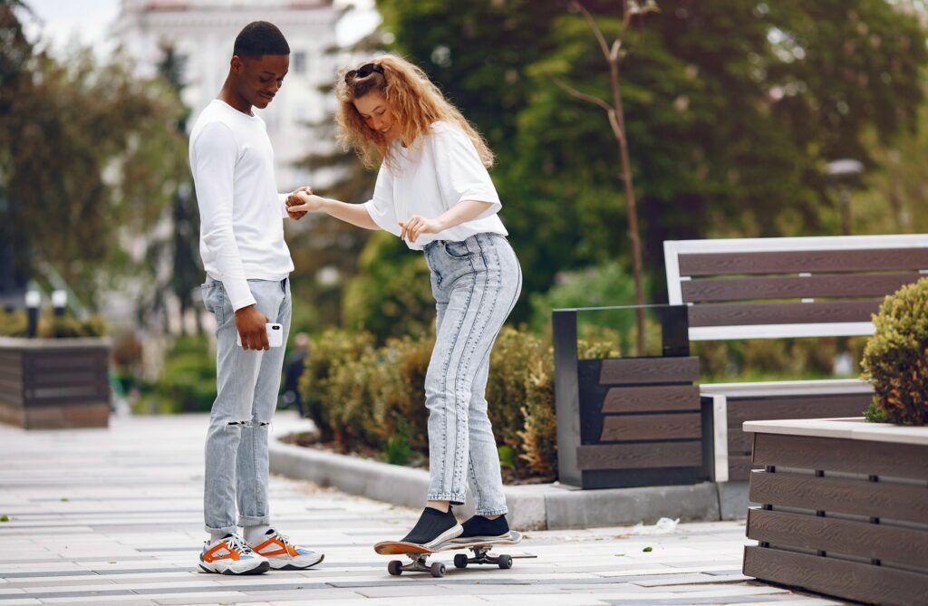 Young couple on an active first date, learning to skate board