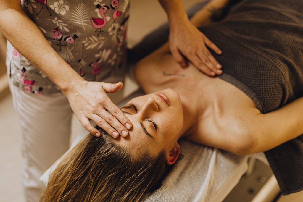 Woman in a somatic coaching session. Her coach has a hand on her forehead, another on her heart.
