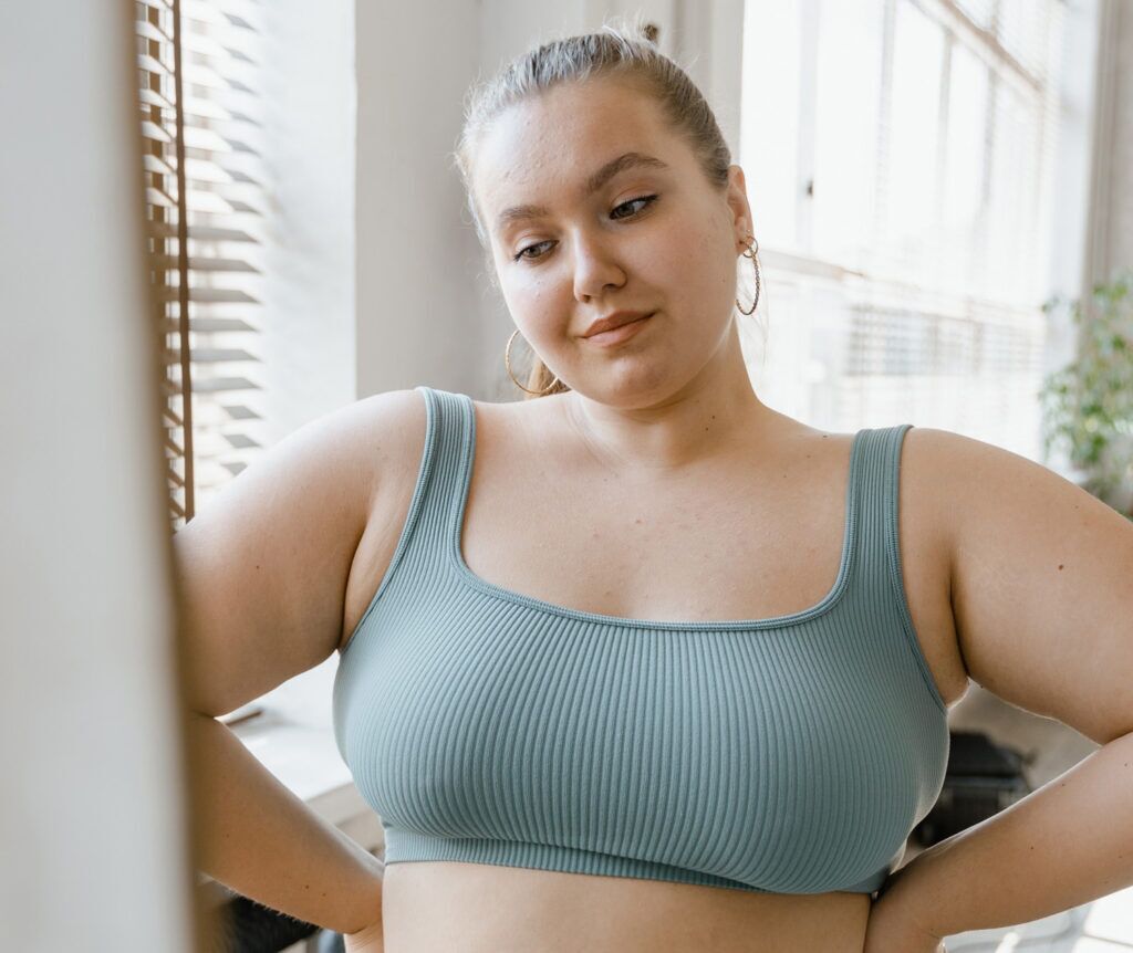 Young woman with body issues looking at herself in the mirror